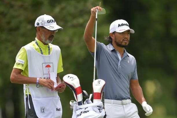Satoshi Kodaira of Japan talks with his caddie on the fifth hole during the third round of the Travelers Championship at TPC River Highlands on June...