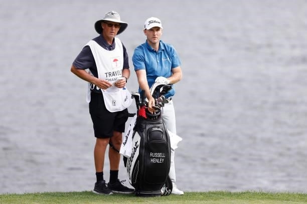 Russell Henley of the United States talks with his caddie on the 17th hole during the third round of the Travelers Championship at TPC River...
