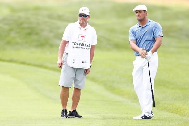 Bryson DeChambeau of the United States talks with his caddie Tim Tucker on the seventh hole during the third round of the Travelers Championship at...
