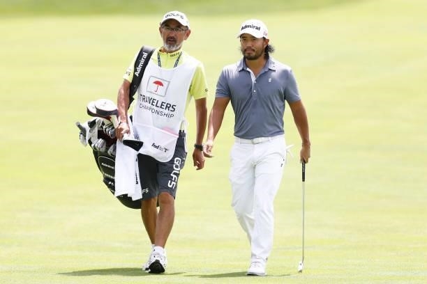 Satoshi Kodaira of Japan walks up the seventh fairway with his caddie during the third round of the Travelers Championship at TPC River Highlands on...