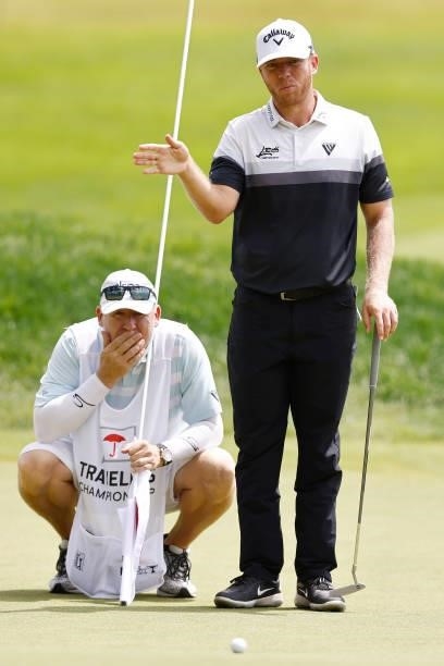 Talor Gooch of the United States talks with his caddie on the seventh green during the third round of the Travelers Championship at TPC River...