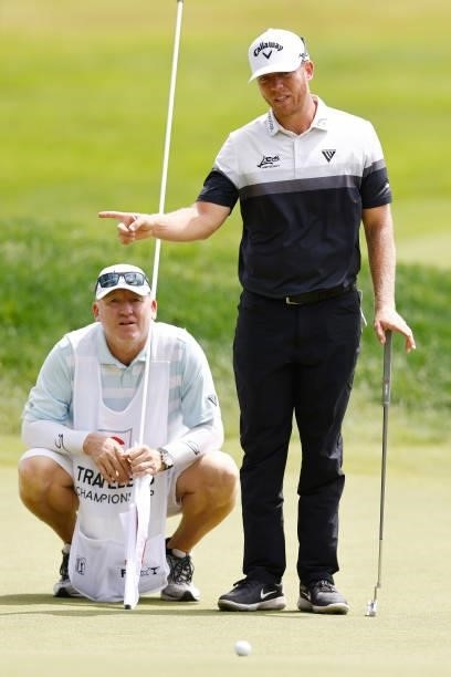 Talor Gooch of the United States talks with his caddie on the seventh green during the third round of the Travelers Championship at TPC River...