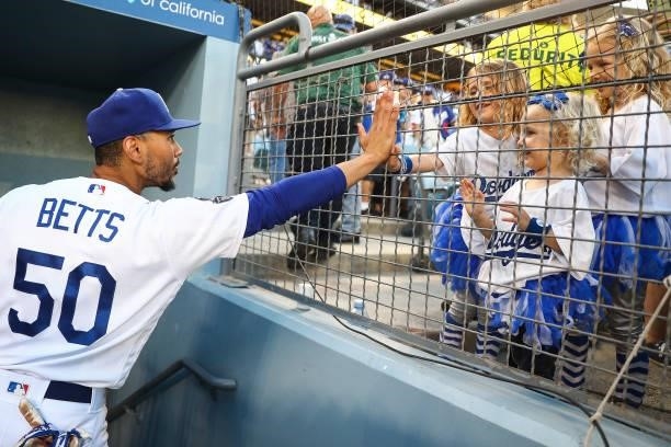 Mookie Betts of the Los Angeles Dodgers high fives with fans after the game against the Chicago Cubs at Dodger Stadium on June 26, 2021 in Los...