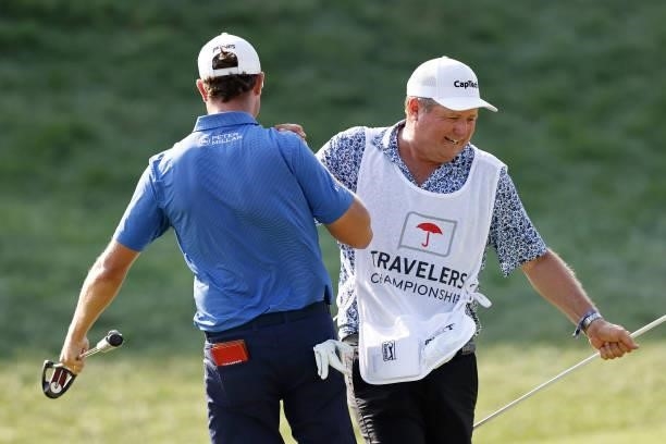 Harris English of the United States celebrates his birdie putt on the 18th green with his caddie during the final round of the Travelers Championship...