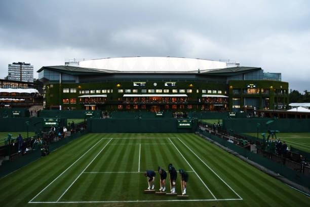 Ground staff sweep court ten as play comes to a close on the outside courts due to a lack of daylight during Day One of The Championships - Wimbledon...