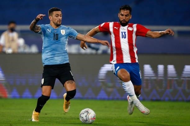 Giorgian De Arrascaeta of Uruguay competes for the ball with Alberto Espinola of Paraguay during a group A match between Uruguay and Paraguay as part...