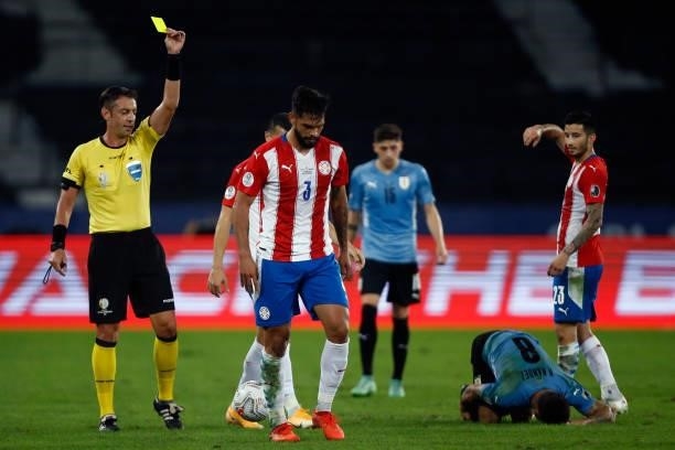Referee Raphael Claus shows a yellow card to Omar Alderete of Paraguay during a group A match between Uruguay and Paraguay as part of Conmebol Copa...