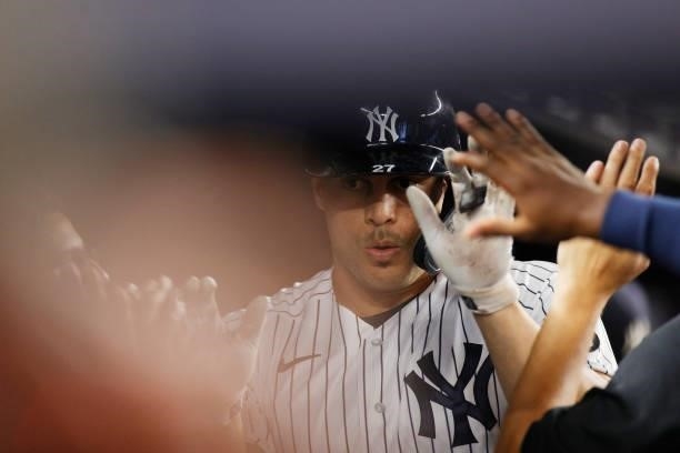 Giancarlo Stanton of the New York Yankees high-fives teammates in the dugout after hitting a solo home run during the sixth inning against the Los...