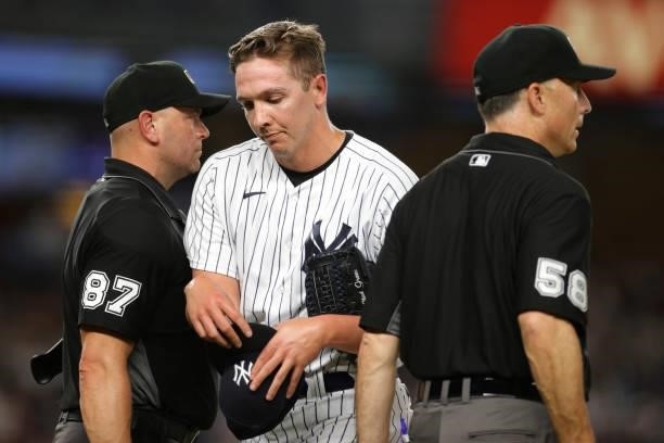 Chad Green of the New York Yankees walks past umpire Scott Barry and Dan Iassogna after they check his glove and hat during the sixth inning against...