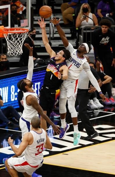 Devin Booker of the Phoenix Suns goes up for a shot against Paul George and Reggie Jackson of the LA Clippers during the second half in Game Five of...
