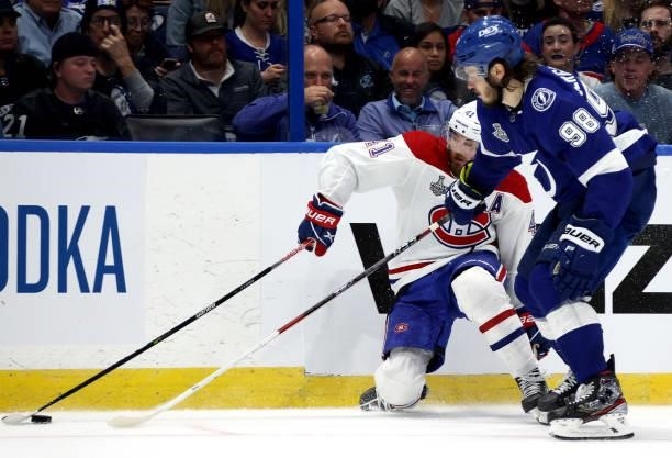 Mikhail Sergachev of the Tampa Bay Lightning collides with Paul Byron of the Montreal Canadiens at the boards during the third period of Game One of...