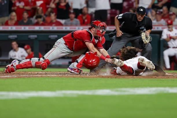 Jonathan India of the Cincinnati Reds slides into home plate to score a run past Andrew Knapp of the Philadelphia Phillies in the eighth inning at...