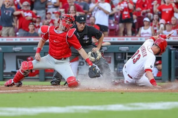 Jesse Winker of the Cincinnati Reds slides into home plate to score a run past Andrew Knapp of the Philadelphia Phillies in the third inning at Great...