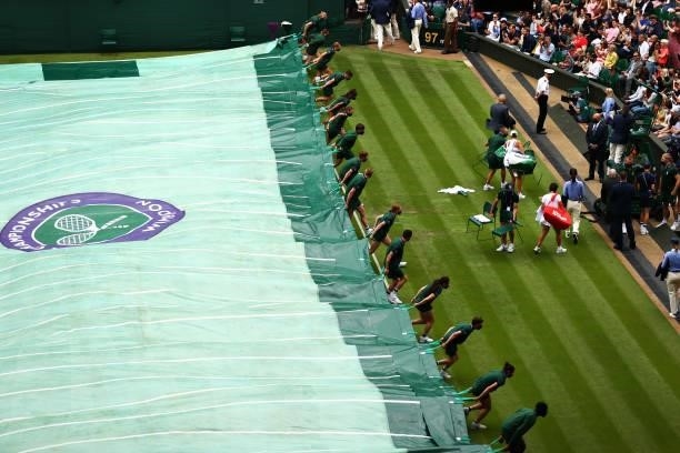 Court coverers pull the covers out as it starts to rain during Day Two of The Championships - Wimbledon 2021 at All England Lawn Tennis and Croquet...