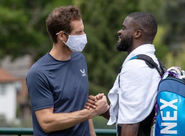 Andy Murray of Great Britain wears a face mask as he greets Frances Tiafoe of United States on the Aorangi Practice Courts during Day Two of The...