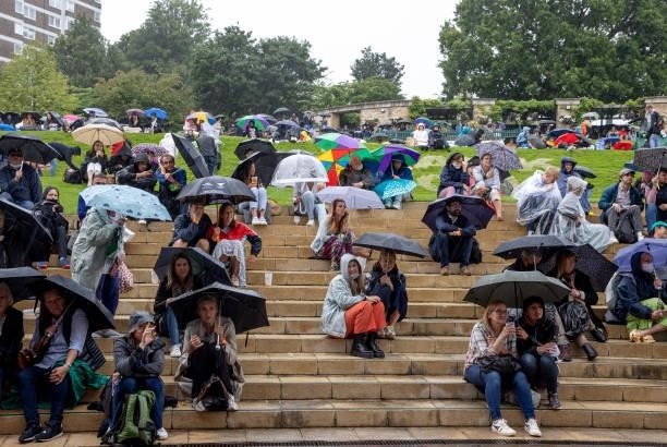 Spectators shelter from the rain on The Hill as they watch the Centre Court action on the large screen during Day Two of The Championships -...