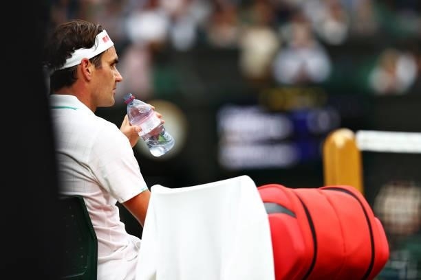 Roger Federer of Switzerland takes a drink as he sits down during a change of ends in his Men's Singles First Round match against Adrian Mannarino of...