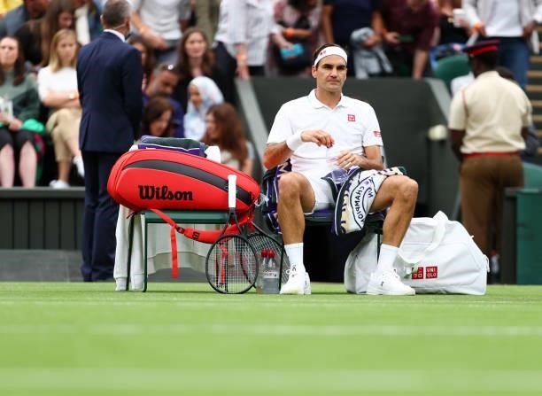 Roger Federer of Switzerland looks on as he sits down during a change of ends in his Men's Singles First Round match against Adrian Mannarino of...