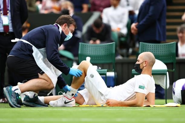 Adrian Mannarino of France receives medical treatment in his Men's Singles First Round match against Roger Federer of Switzerland during Day Two of...