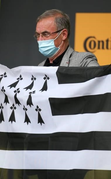 Five time Tour de France winner Bernard Hinault holds the flag of Brittany during the podium ceremony of stage 4 of the 108th Tour de France 2021, a...
