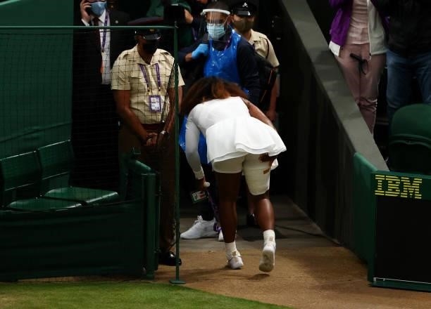 Serena Williams of The United States holds her leg as she walks off the court after retiring from her Ladies' Singles First Round match against...
