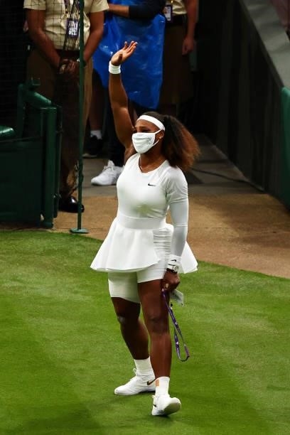 Serena Williams of The United States waves to the fans as she leaves the court after retiring from the match with an injury in her Ladies' Singles...