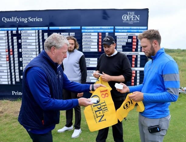 Sam Forgan of England is presented with a commemorative pin flag and players bag tag by John Clark of the R&A in front of the main scoreboard after...