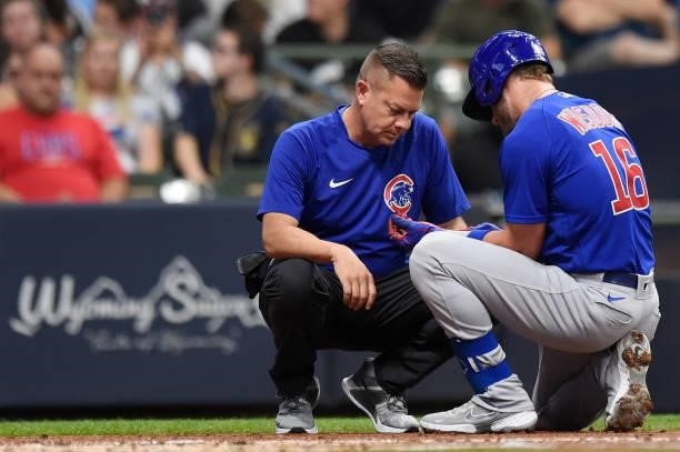 Patrick Wisdom of the Chicago Cubs is attended to by a trainer after being hit by a pitch in the second inning against the Milwaukee Brewers at...