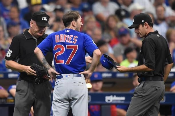 Umpires Jeff Nelson and Pat Hoberg check the hat, glove, and belt of Zach Davies of the Chicago Cubs after the bottom of the second inning against...