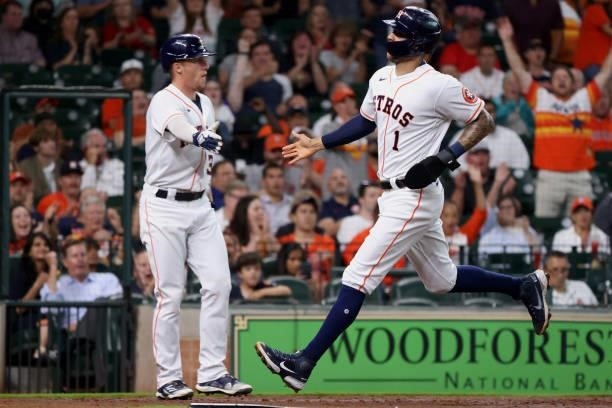 Carlos Correa of the Houston Astros high fives Myles Straw after scoring on a sacrifice fly hit by Abraham Toro during the second inning against the...