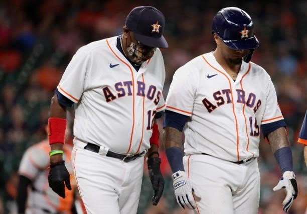 Martin Maldonado of the Houston Astros walks to first alongside manager Dusty Baker Jr. #12 after being hit on the hand by a pitch from Travis Lakins...