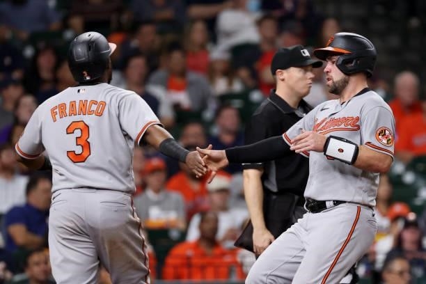 Austin Wynns of the Baltimore Orioles and Maikel Franco high five after being driven in by Austin Hayes during the fifth inning against the Houston...