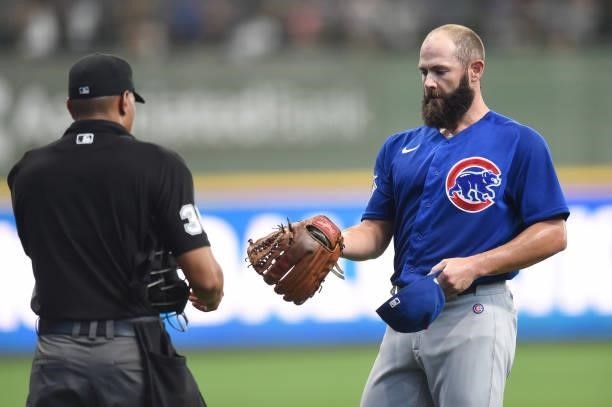 Jake Arrieta of the Chicago Cubs hands his hat and glove to home plate umpire Jeremie Rehak after the bottom of the first inning against the...