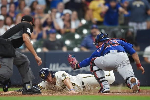 Tyrone Taylor of the Milwaukee Brewers slides safely into home plate ahead of the tag by Willson Contreras of the Chicago Cubs in the fourth inning...