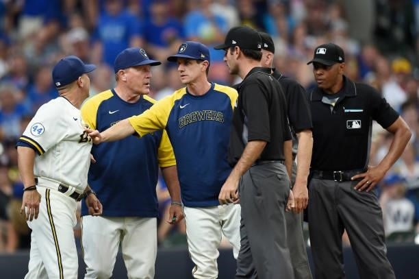Hitting coach Andy Haines of the Milwaukee Brewers argues with home plate umpire Jeremie Rehak after Christian Yelich was called out on strikes in...