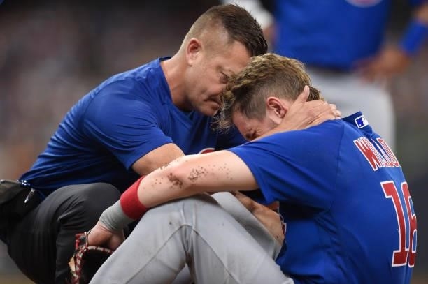 Patrick Wisdom of the Chicago Cubs is attended to by the trainer after being injured on a play at first base in the second inning against the...