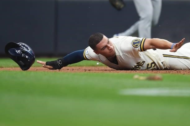 Tyrone Taylor of the Milwaukee Brewers slides safely into home plate ahead of the tag by Willson Contreras of the Chicago Cubs in the fourth inning...