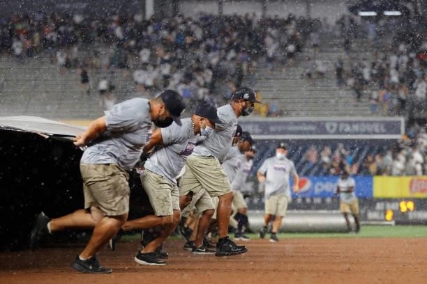 Grounds crew members bring the tarp over the field for a rain delay during the third inning between the Los Angeles Angels and the New York Yankees...