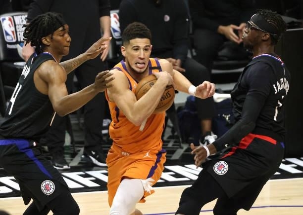 Devin Booker of the Phoenix Suns drives to the basket between Terance Mann and Reggie Jackson of the LA Clippers during the first half in Game Six of...