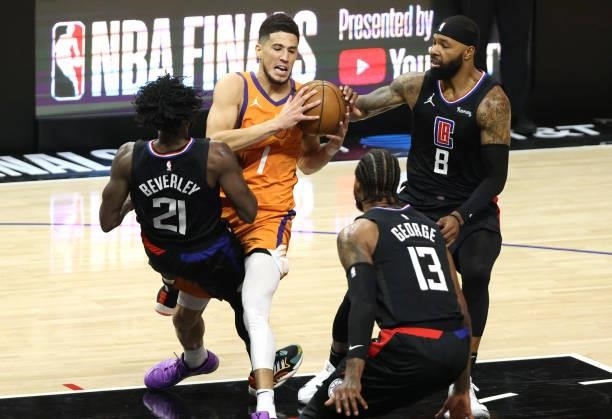 Devin Booker of the Phoenix Suns is called for charging against Patrick Beverley of the LA Clippers as Marcus Morris Sr. #8 and Paul George look on...