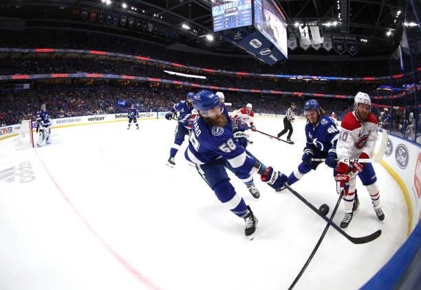 David Savard and Mikhail Sergachev of the Tampa Bay Lightning battle in the corner with Joel Armia of the Montreal Canadiens during the third period...