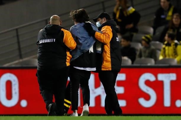 Ground invader is removed by security staff during the round 16 AFL match between the Gold Coast Suns and the Richmond Tigers at Marvel Stadium on...