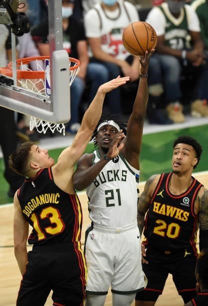 Jrue Holiday of the Milwaukee Bucks goes up for a shot against Bogdan Bogdanovic and John Collins of the Atlanta Hawks in Game Five of the Eastern...