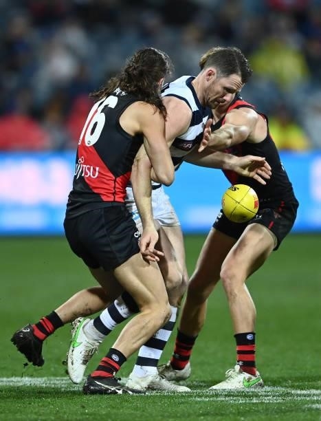 Patrick Dangerfield of the Cats kicks whilst being tackled by Archie Perkins of the Bombers during the round 16 AFL match between Geelong Cats and...