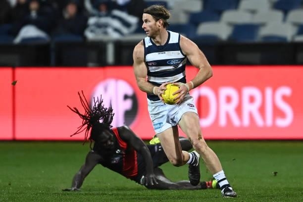 Lachie Henderson of the Cats gathers the ball infront of Anthony McDonald-Tipungwuti of the Bombers during the round 16 AFL match between Geelong...