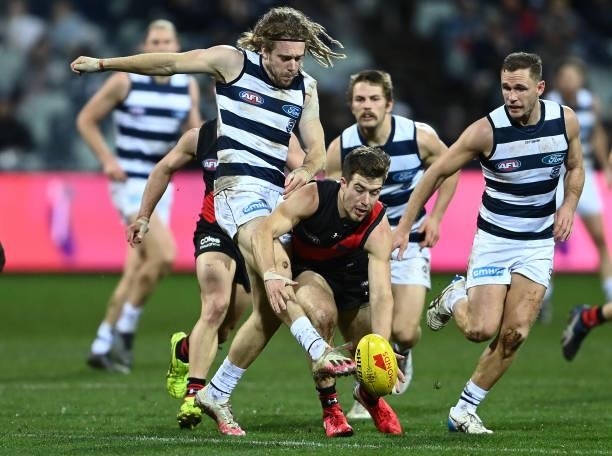Zach Merrett of the Bombers smothers a kick by Cameron Guthrie of the Cats during the round 16 AFL match between Geelong Cats and Essendon Bombers at...