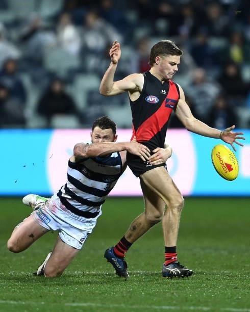 Brayden Ham of the Bombers kicks whilst being tackled by Patrick Dangerfield of the Cats during the round 16 AFL match between Geelong Cats and...