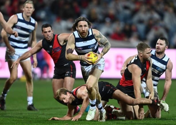Zach Tuohy of the Cats breaks free of a tackle by Darcy Parish of the Bombers during the round 16 AFL match between Geelong Cats and Essendon Bombers...