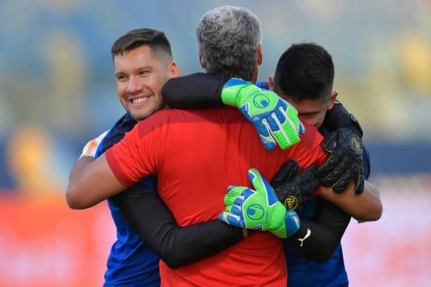 Gerardo Ortiz of Paraguay and teammate Alfredo Aguilar hug goalkeeper's trainer Roberto Bonanano prior to a quarterfinal match between Peru and...