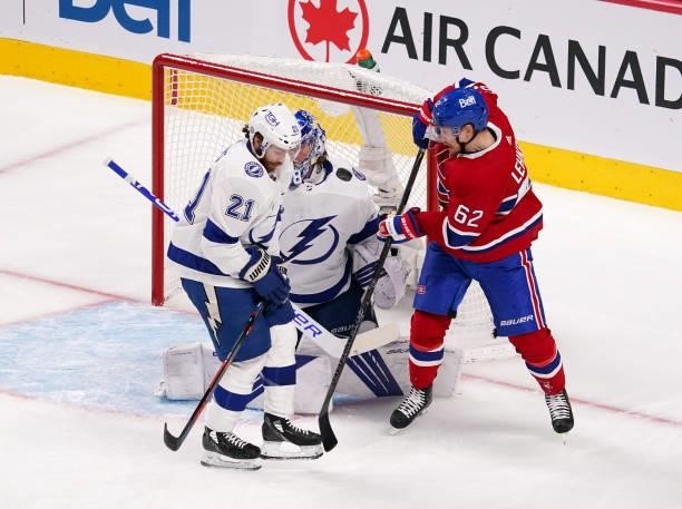 Artturi Lehkonen of the Montreal Canadiens and Brayden Point of the Tampa Bay Lightning battle for possession as Andrei Vasilevskiy tends goal during...
